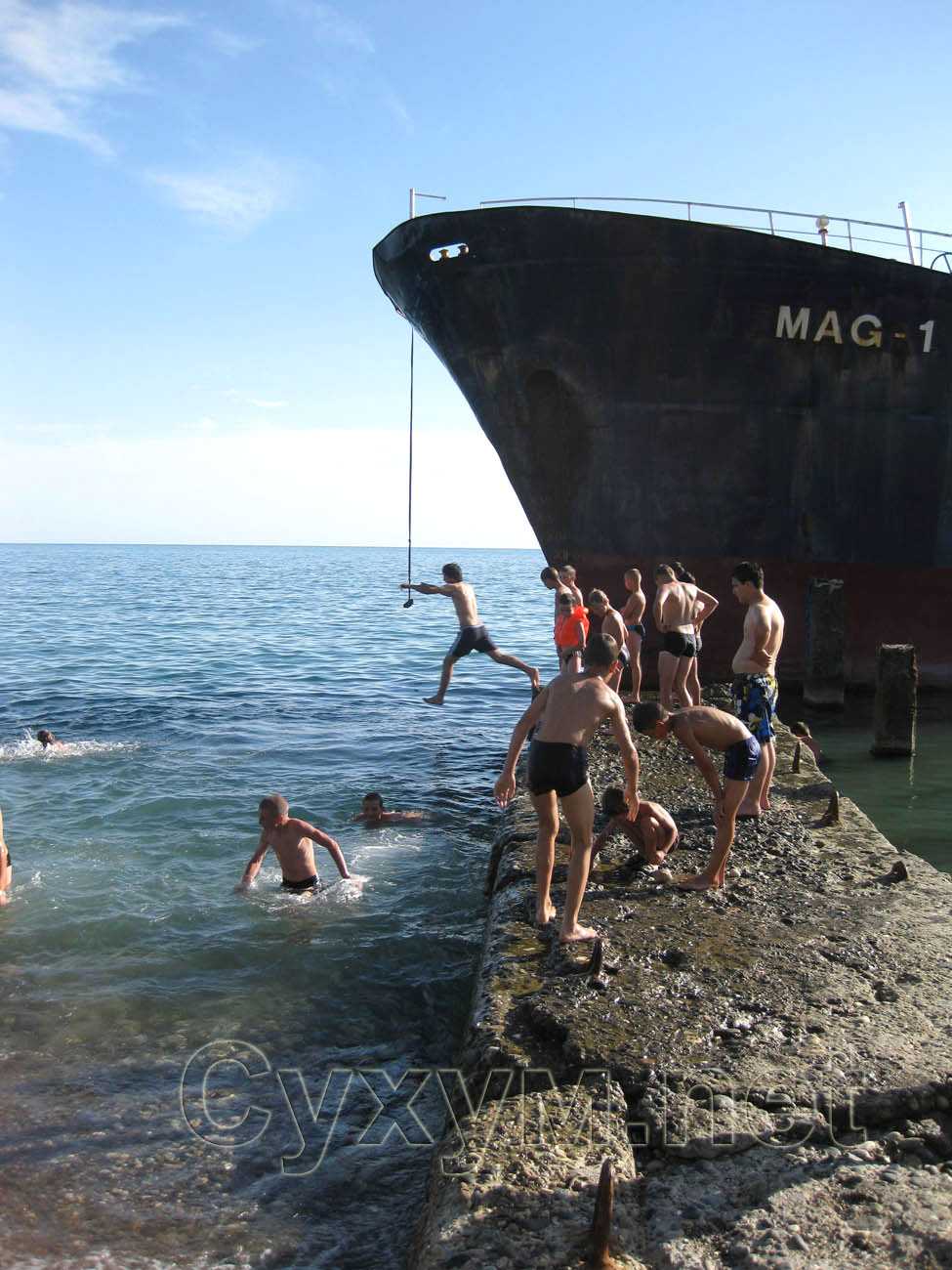 молодые ребята ныряют возле корабля